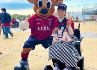 車いす観戦「場所選べるように」 鹿島のマスコットと写真に収まるサポーターの宇野さん=2023年10月28日、茨城県鹿嶋市のカシマサッカースタジアムで(宇野さん提供)